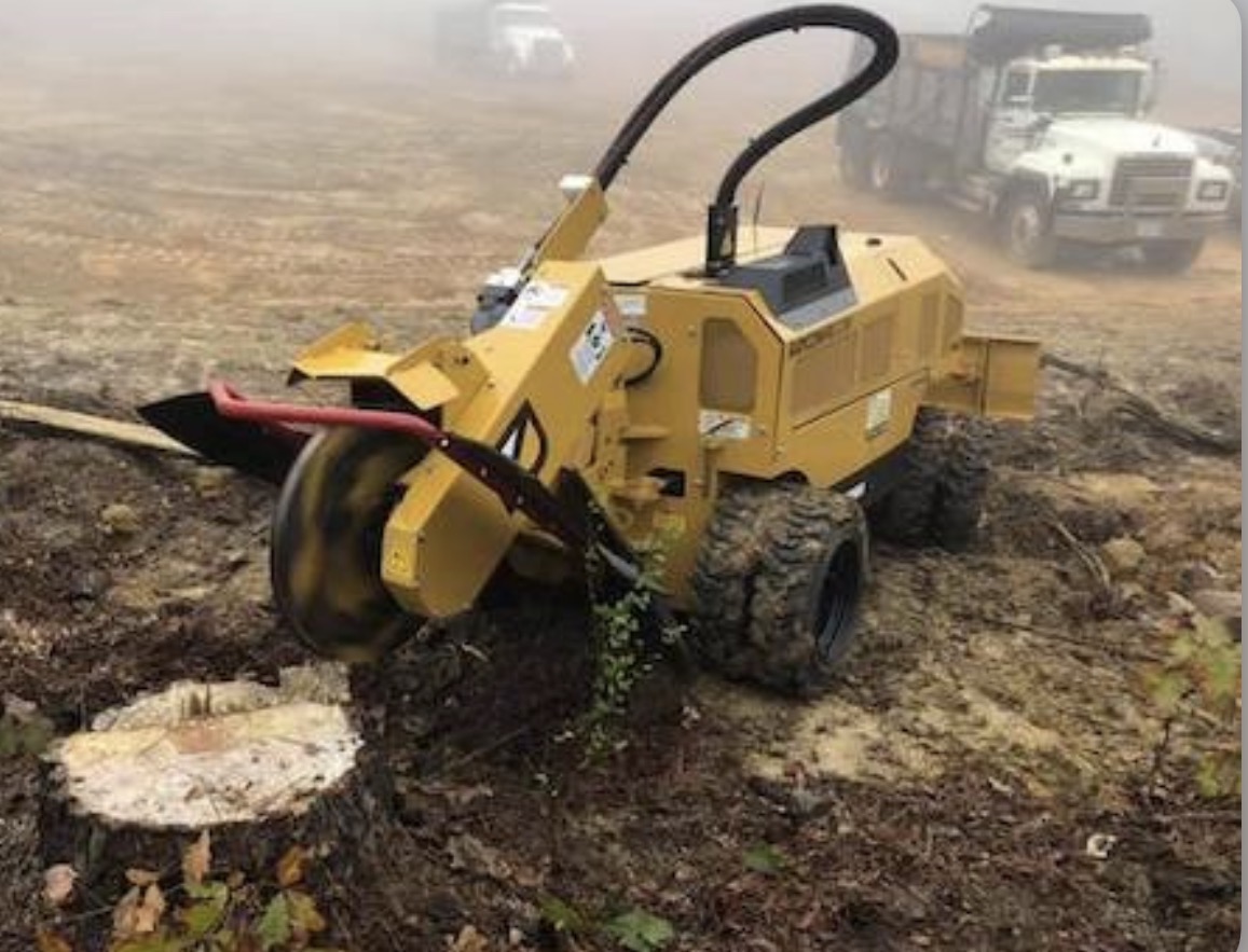 Self-propelled stump grinder working a cleared lot on a foggy morning