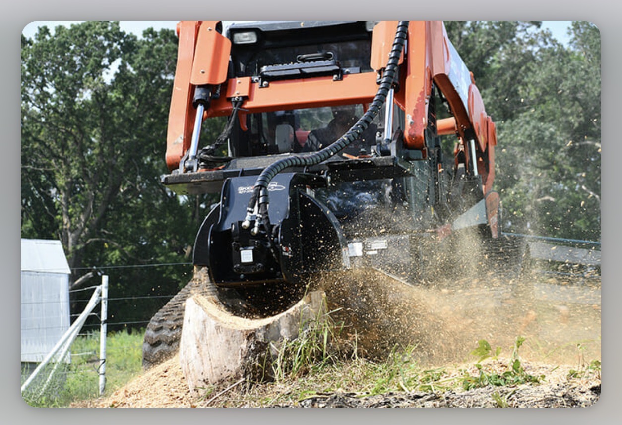 Skid-steer stump grinder attachment throwing chips off a large stump